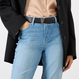 Model wearing LAgence light blue slim jeans styled with a black blazer, satin blouse, and black leather belt.