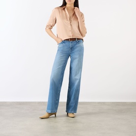 Model wearing L'Agence light blue wide leg jeans in 100% cotton denim, styled with a blush shirt, tan belt and beige heeled mules.