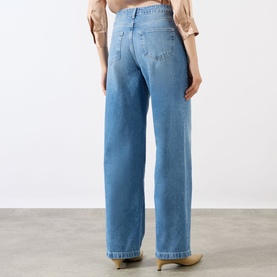 Model wearing LAgence light blue wide leg jeans in 100% cotton, rear view, styled with a cropped beige top.