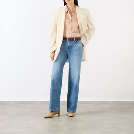 Model wearing LAgence Light Blue Wide Leg Jeans, styled with a cream blazer, peach shirt, brown belt and beige heeled mules.