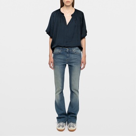 Model wearing Zadig blue bootcut jeans with mid-rise waist, styled with a dark navy loose-fit top and grey trainers.