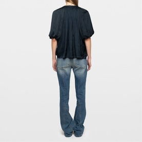Model wearing Zadig blue short-sleeve gathered top with balloon sleeves, styled with mid-wash flared jeans, back view