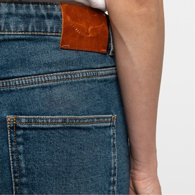 Close-up of Zadig blue denim jeans showing back pocket detail with tan leather logo patch and stitching
