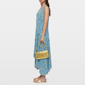 Model carrying Zadig yellow metallic shoulder bag with gold hardware, styled with blue floral maxi dress and tan sandals