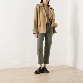 Model wearing Paige Quincy Ankle Straight-Leg Jeans in Vintage Ivy Green, styled with a camel short trench coat and black loafers.