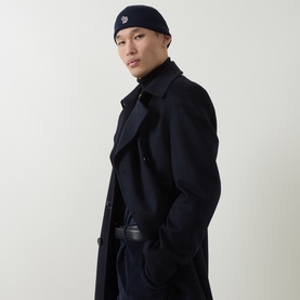 Model with Paul Smith Access Zebra Logo Beanie Hat in blue, styled with a navy wool overcoat and black turtleneck