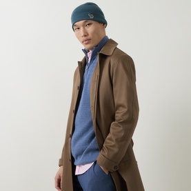 Model with Paul Smith Access Zebra Logo Beanie Hat in blue, styled with a brown mac coat and blue knit sweater over pink shirt.