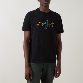 Model wearing Paul Smith Mushrooms Logo T-Shirt in black with multicolour mushroom graphic print on chest, styled with dark green trousers.