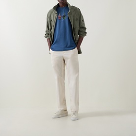 Model wearing Paul Smith Indigo Crew Neck T-Shirt with graphic print, styled with olive jacket and cream trousers.