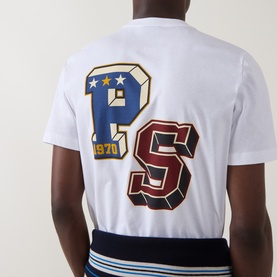 Model wearing Paul Smith white cotton crew neck T-shirt, back view showing large varsity PS logo patch in blue and red with gold stars.