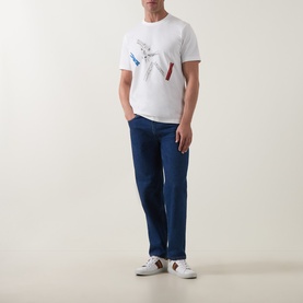 Model wearing Paul Smith Off White Crew Neck T-Shirt with hummingbird print, styled with navy trousers and white trainers.