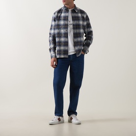 Model wearing Paul Smith Off White Crew Neck T-Shirt, styled with grey check overshirt, blue jeans and white trainers.