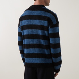 Model wearing Paul Smith Black and Blue striped wool blend crew neck jumper, shot from behind, paired with black trousers.