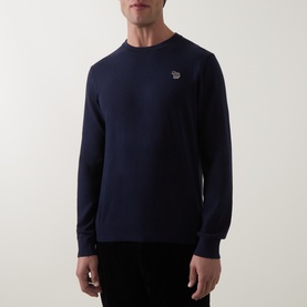 Model wearing Paul Smith crew neck knit in very dark navy, featuring signature zebra logo badge on chest, paired with dark trousers.