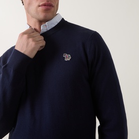 Model wearing Paul Smith navy blue cotton crew neck jumper with zebra logo badge, styled over a light blue collared shirt.