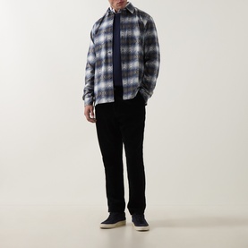 Model wearing Paul Smith Very Dark Navy cotton crew neck, styled with grey plaid overshirt and black trousers.