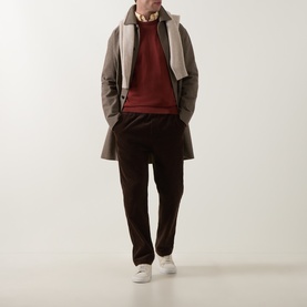 Model wearing Paul Smith Brick Red cotton crew neck, styled with grey overcoat, dark brown trousers, and white trainers.