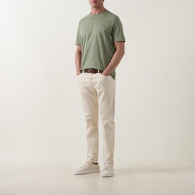 Model wearing Paul Smith light grey-green cotton crew neck T-shirt, styled with cream trousers, brown belt and white trainers.