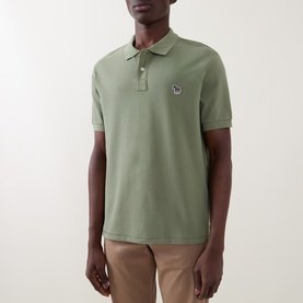 Model wearing Paul Smith polo shirt in light grey-green cotton piqu&eacute;, featuring zebra logo badge, short sleeves, and three-button placket.