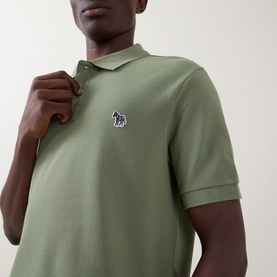 Model wearing Paul Smith polo in light grey-green cotton piqu&eacute; with embroidered zebra logo badge on chest