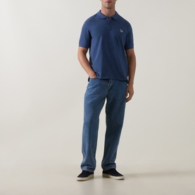 Model wearing Paul Smith Indigo polo shirt with small chest logo, styled with light blue jeans and dark canvas shoes