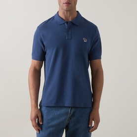 Model wearing Paul Smith Indigo polo shirt with zebra logo patch, styled with blue jeans. Short-sleeved piqu&eacute; cotton with button placket.