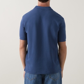 Model wearing Paul Smith Polo in Indigo, rear view, 100% cotton piqu&eacute; fabric, short sleeves, paired with light blue jeans.