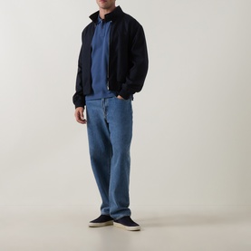 Model wearing Paul Smith Indigo cotton polo with black bomber jacket, light blue straight-leg jeans and navy canvas shoes.