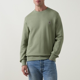 Model wearing sage green crew neck sweatshirt with embroidered zebra logo, styled with light blue jeans