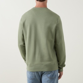 Model wearing sage green crew neck sweatshirt, back view, styled with light blue jeans
