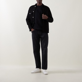 Model wearing Paul Smith black cotton sweatshirt with black overshirt, dark grey jeans and white low-top trainers.