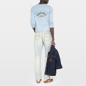 Model wearing Zadig blue sweatshirt with back graphic print, styled with light-wash straight-leg jeans, carrying a denim jacket.