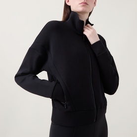 Model wearing Spanx AirEssentials&reg; Track Jacket in Very Black with mock neck, zip fastening, dropped shoulders and ribbed cuffs