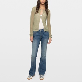 Model wearing Zadig green fine knit cardigan, styled with white top, blue flare jeans and grey trainers