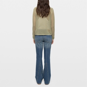 Model wearing Zadig green long sleeve sheer top, styled with blue flare jeans, shot from behind