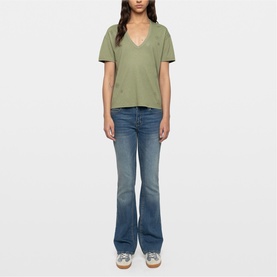 Model wearing Zadig green V-neck short sleeve T-shirt with distressed detail, styled with blue flare jeans and white trainers