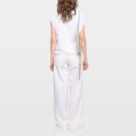 Model wearing Zadig white wide-leg trousers and white top, back view, styled with a silver chain shoulder bag