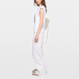 Model wearing Zadig white wide-leg trousers and sleeveless top, styled with a embellished tote bag and strappy sandals