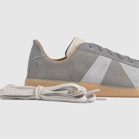 Adidas trainer in dove grey suede with white panel, gum sole, and grey flat laces displayed alongside shoe.
