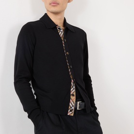 Model wearing black long-sleeve shirt, open to reveal Burberry check lining, styled with black trousers and belt