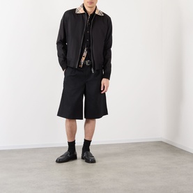 Model wearing Burberry Glenfields Harrington Jacket in black with check collar, styled with black shorts and black leather shoes.