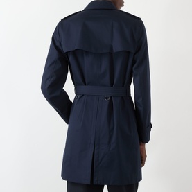 Model wearing Burberry Kensington Heritage Trench Coat in coal blue, showing back view with storm flap, rear vent, epaulettes and matching belt.