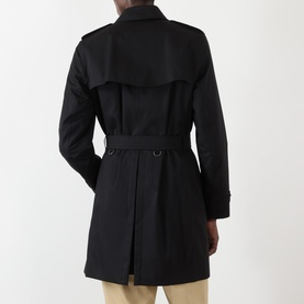 Model wearing Burberry Kensington Heritage Trench Coat in black, rear view showing storm flap, belt, and rear vent detail.