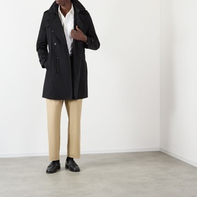 Model wearing Burberry Kensington Heritage Trench Coat in black, double-breasted, styled with beige trousers and black leather shoes.