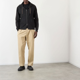 Model wearing Burberry Scott Embroidered Logo Zip Hoodie in black with contrast piping, styled with beige trousers and dark trainers.