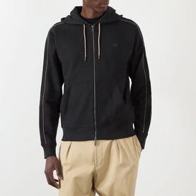 Model wearing Burberry Scott Embroidered Logo Zip Hoodie in black with contrast piping, styled with beige tailored trousers.