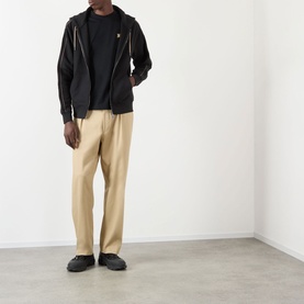 Model wearing Burberry Scott Embroidered Logo Zip Hoodie in black with contrast piping, styled with beige trousers and black shoes.