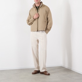 Model wearing Burberry saltmarsh beige cotton jacket with inner gilet, styled with cream trousers and brown leather loafers.