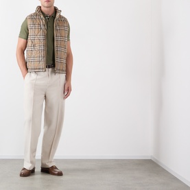 Model wearing Burberry saltmarsh beige Vintage Check gilet, styled with olive polo shirt and cream trousers.