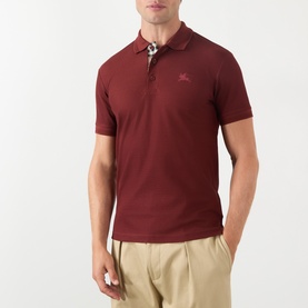 Model wearing Burberry red cotton polo shirt with check-trim collar, embroidered logo to chest, styled with beige trousers.